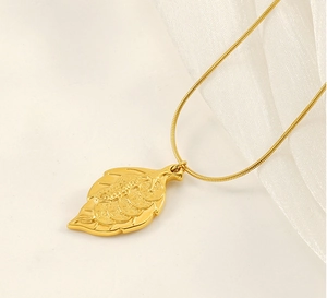 Macro detail of leaf pendant with ancient coin relief on gold snake chain necklace