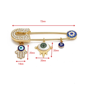 Detailed view of gold Hamsa Hand and Evil Eye brooch pin with crystal and enamel accents