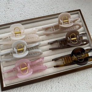 Set of minimalist large hair claws in various elegant colors on a beige velvet tray