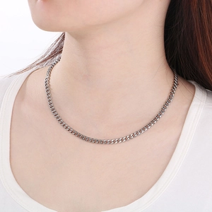 Close-up of polished silver cuban link necklace worn by male model on white collar