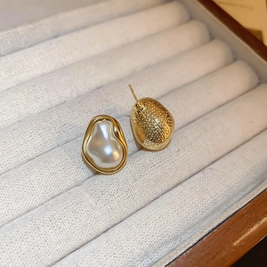 Macro view of Baroque pearl earrings with irregular gold metal texture on velvet tray