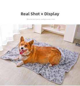 Cozy gray flannel pet blanket with paw print pattern shown with a Corgi dog