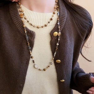 Detail of layered retro beaded necklace with gold accents on a warm knit sweater