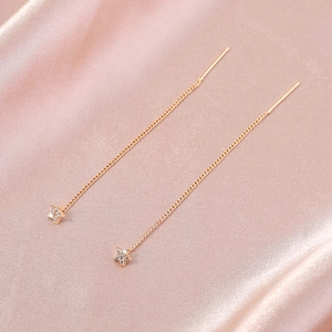 Close-up of golden star drop earrings with sparkling cubic zirconia on pink silk fabric