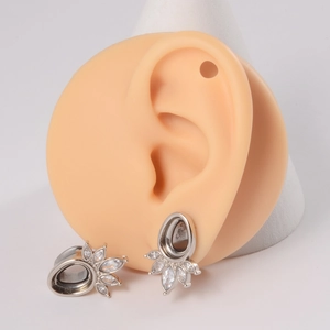 Detail of silver teardrop petal ear tunnel with white zircons on a silicone ear model