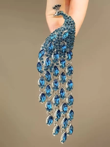 Macro view of crystal peacock brooch with blue teardrop stones and silver tassels