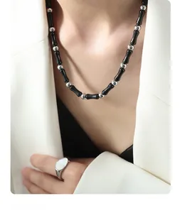 Close-up of black onyx beaded necklace and mother of pearl ring on a model in white blazer
