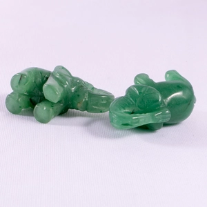 Detail view of two hand-carved green jade elephant figurines with smooth polished texture