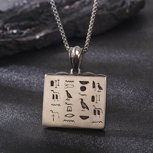 Detail of vintage square stainless steel pendant with engraved Egyptian hieroglyphs