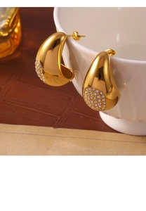 Détail de boucles d'oreilles goutte d'or avec oxydes de zirconium sur tasse céramique