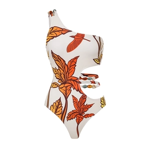 Detail of white one-shoulder swimsuit featuring tropical leaf print and beaded side cutouts