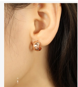 Macro shot of rose gold C-shaped earrings featuring a classic quilted pattern engraving