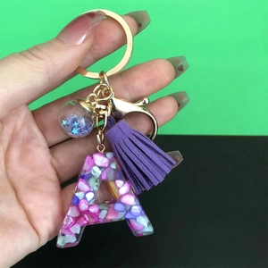 Detail of resin letter A keychain with purple stones, tassel and gold metal hardware