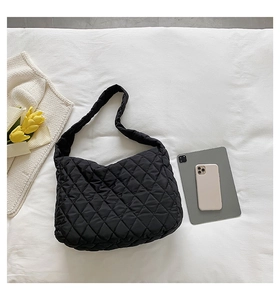 Detail of black quilted cloud bag showing soft padded texture next to an iPad and smartphone