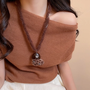 Vue détaillée d'un collier pendentif cœur léopard en peluche sur un pull en maille marron