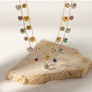 Detail of gold and silver shell pendants with colorful zircons on stone display