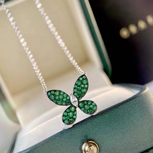 Macro shot of silver butterfly necklace with green emerald pave wings and marquise diamond