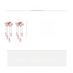 Detail view of cloud-shaped faux pearl earrings with long tassels and pink crystals