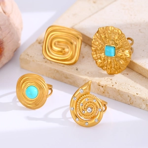 Detail of four gold rings with turquoise stones and rhinestones on travertine base