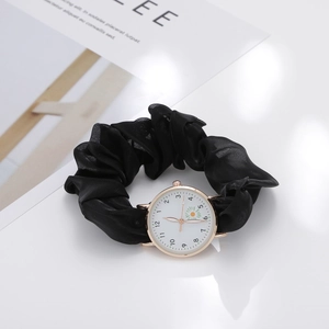 Detail of white quartz watch with golden case and black fabric floral scrunchie strap