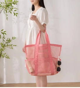 Detail der rosa Strandtasche aus Netzstoff mit vielen Taschen und Platz für Sonnencreme