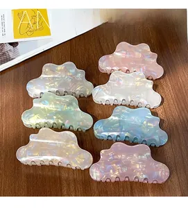 Detail of colorful cloud-shaped acetate hair claws in iridescent pastel colors on wood