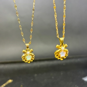 Elegant gold titanium necklace set with pearl and shell bow pendants on gray background