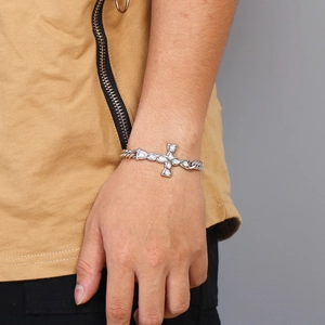 Detail of silver stainless steel cross bracelet with white pearls worn on a wrist