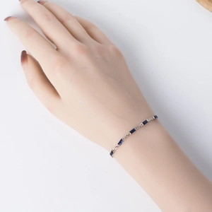Close-up of S925 sterling silver bracelet with emerald-cut blue cubic zirconia on wrist