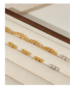 Detail of gold and silver beaded titanium earrings displayed in a linen jewelry box