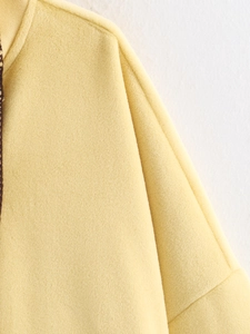 Detailed close-up of light yellow wool blend cloak fabric texture and collar stitching