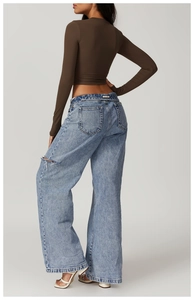 Detail of light blue washed wide-leg jeans with distressed rip and pocket from back view