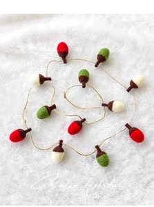 Detailed macro view of wool felt acorn ornaments in green, red, and cream colors