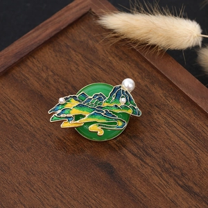 Macro detail of enamel gourd brooch with green stone base and pearl accents on wood