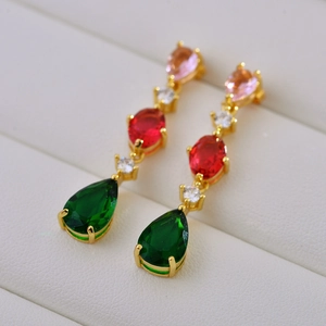 Macro view of long colorful crystal drop earrings with green pear-shaped gemstones