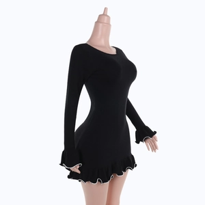 Detalle de ribete blanco en vestido de punto negro con volantes ondulados en el dobladillo