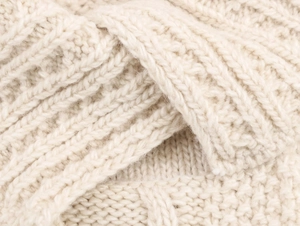 Detailaufnahme von cremeweißem Zopfstrickgewebe mit dicker Wolltextur und Rippenmuster