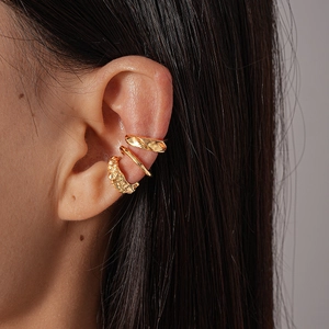 Close-up of three irregular geometric gold ear cuffs worn on the cartilage in a minimalist style