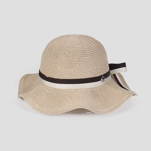 Close-up of wavy brim sun hat with woven texture, black and white ribbon, and flower buckle