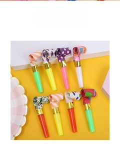 Flat lay of colorful polka dot party blowouts with plastic mouthpieces on yellow background