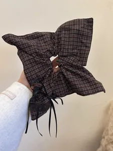 Close-up of brown plaid oversized scrunchie with long black ribbons and linen texture