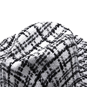 Detailed close-up of black and white houndstooth tweed fabric texture on fedora hat
