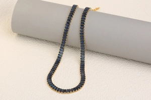 Detailed shot of 18K gold plated necklace with square-cut blue gemstone on a pedestal