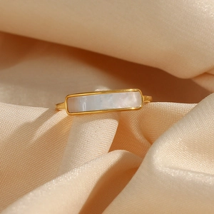 Macro detail of gold plated stainless steel ring featuring a rectangular shell inlay on silk