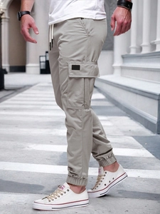 Detail view of khaki cargo pants featuring large side pockets and ribbed elastic cuffs