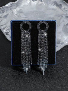 Macro shot of long dark grey crystal tassel earrings displayed in a luxury blue jewelry box