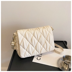 Close-up of cream quilted crossbody bag with gold hardware and fine faux leather texture