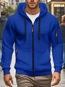 Detail of royal blue zip-up hoodie featuring orange zipper pullers and sleeve pocket