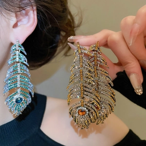 Macro view of crystal-encrusted peacock feather earrings with colorful gradient rhinestones