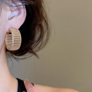 Macro shot of gold mesh C-shaped hoop earrings with intricate textured lattice design